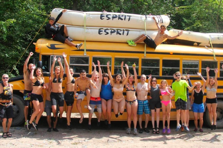 a group of people standing in front of a school bus