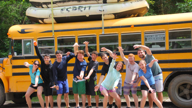 a group of people standing in front of a school bus